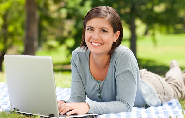 Mujer que trabaja en su computadora portátil en el parque