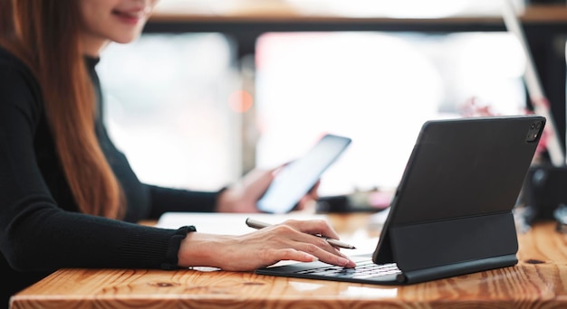 Mujer que trabaja en una tableta portátil, manos femeninas que escriben el primer plano del teclado, mujer de negocios o estudiante que usa una computadora portátil en el café.