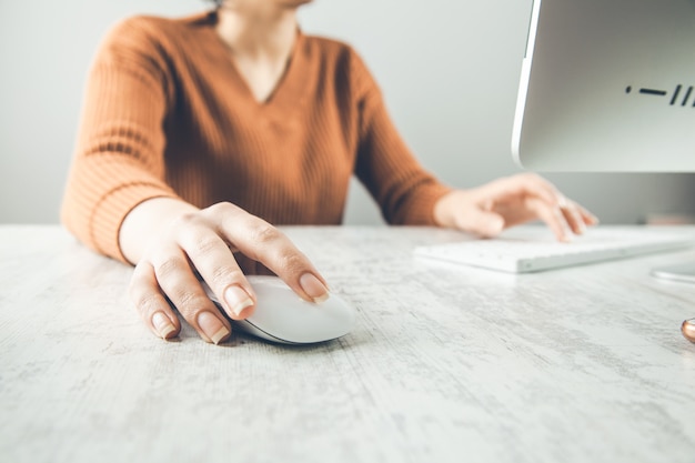 Mujer que trabaja en el teclado de la computadora en el escritorio