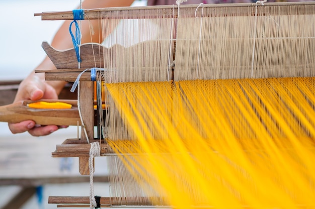 Mujer que trabaja en el telar tradicional tailandés en el trabajo con hilandero