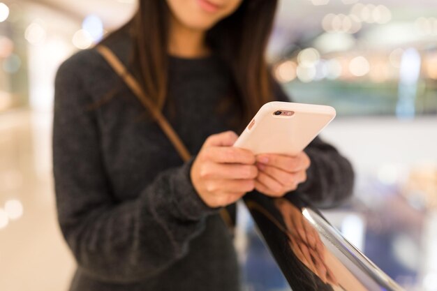 Mujer que trabaja en el teléfono celular en el centro comercial