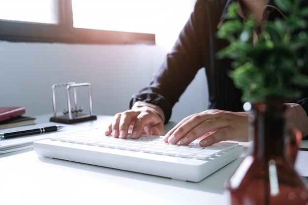 Mujer que trabaja usando una computadora portátil en la mesa de madera. Manos escribiendo en un teclado