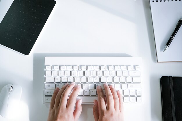 Foto mujer que trabaja usando una computadora portátil en la mesa de madera. manos escribiendo en un teclado