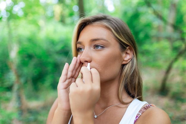Mujer que usa aerosol nasal al aire libre para el tratamiento de la alergia al polen de los árboles