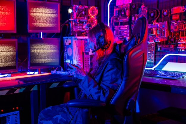 Mujer que usa auriculares de juego jugando juegos de esports sala de juegos de consola Jugador que usa un controlador de joystick para un torneo de carreras juega videojuegos en línea con luces de neón de computadora