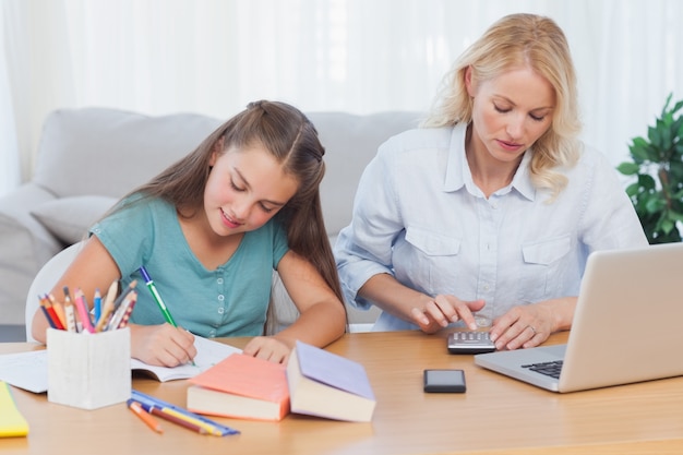 Mujer que usa la calculadora en el escritorio en la sala de estar