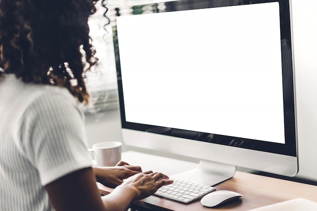 Mujer que usa la computadora con maqueta de pantalla en blanco en loft de trabajo moderno