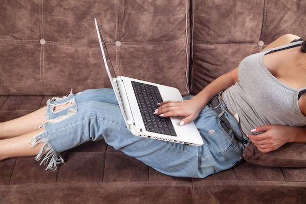 Mujer que usa una computadora portátil blanca en casa
