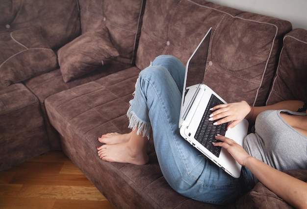 Mujer que usa una computadora portátil blanca en casa.