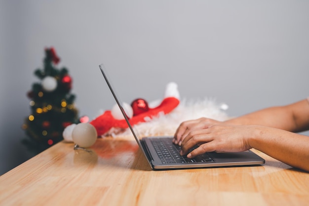 Mujer que usa computadora portátil en el interior para pagar productos del comercio electrónico navideño