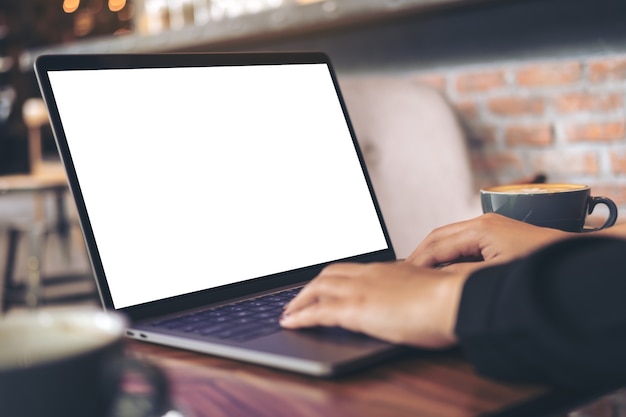 Mujer que usa la computadora portátil de la maqueta con la taza de café