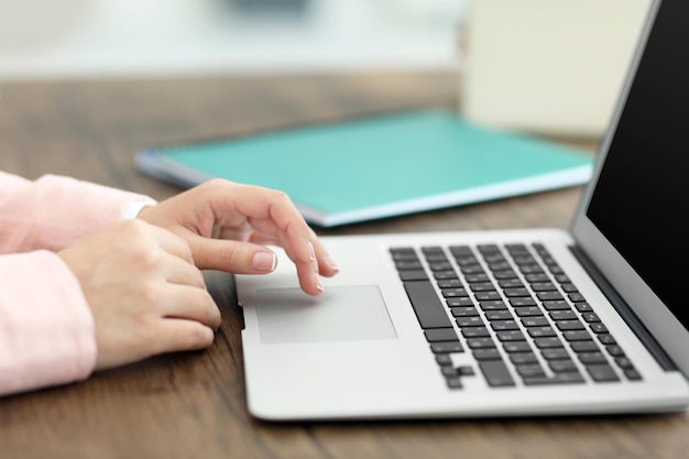 Mujer que usa la computadora portátil en la mesa en la oficina