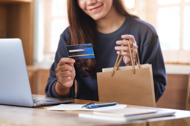 Una mujer que usa una computadora portátil y una tarjeta de crédito para comprar en línea en casa