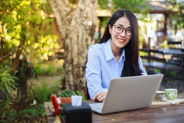 mujer que usa la computadora portátil y tomando café en el jardín