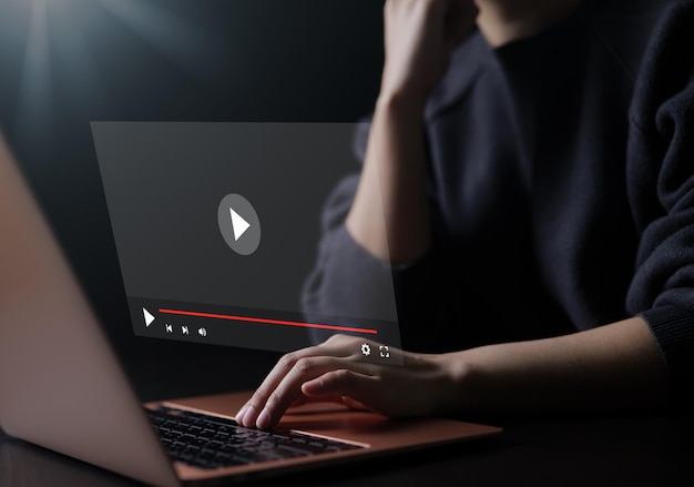 Mujer que usa una computadora para transmitir en línea en una pantalla virtual viendo video en Internet espectáculo de contenido en vivo o contenido tutorial en línea transmisión de concierto en vivo en línea webinar de medios digitales