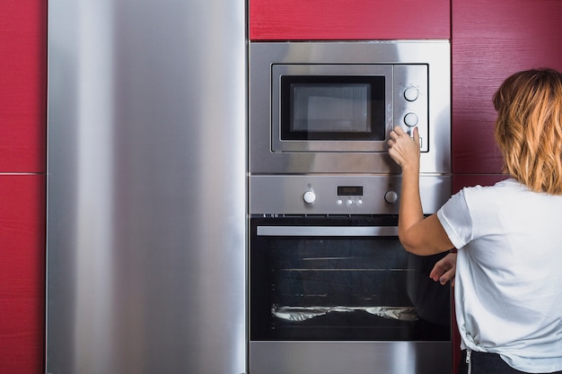 Foto mujer que usa el horno de microondas moderno