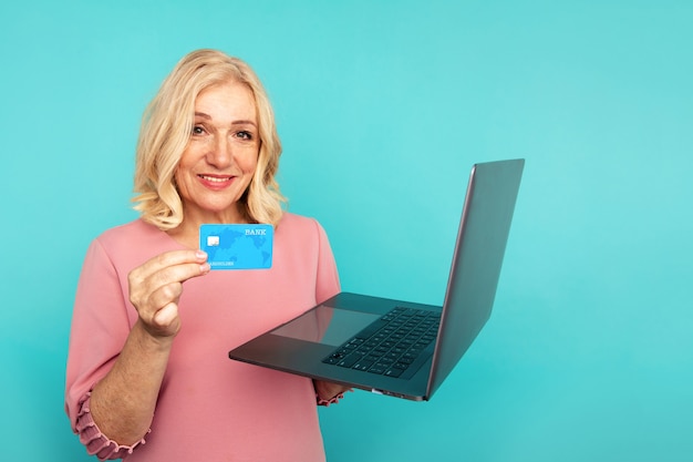 Mujer que usa internet para compras en línea con computadora y tarjeta de crédito.