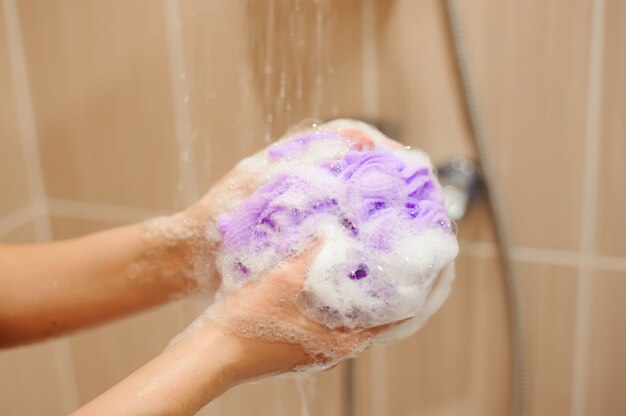 Mujer que usa un jabón mientras toma una ducha en el baño.