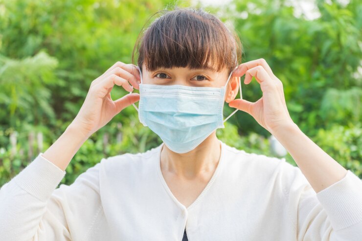 Una mujer que usa una máscara facial con una cara feliz para prevenir el polvo, la propagación de gérmenes y bacterias y evitar las infecciones por el virus corona. Concepto de higiene