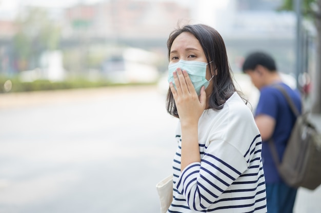 La mujer que usa una máscara facial protege el filtro contra la contaminación del aire (PM2.5) o usa una máscara N95