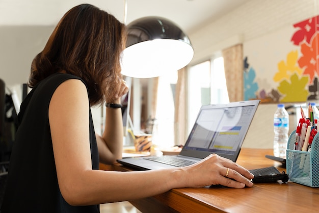 Mujer que usa un ratón que trabaja en la computadora portátil