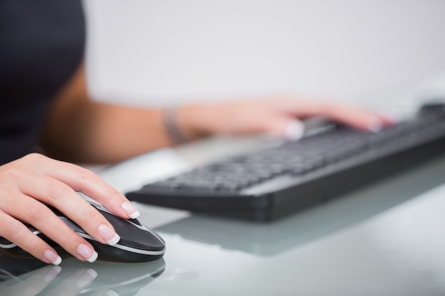 Foto mujer que usa el ratón y el teclado de la computadora en el escritorio