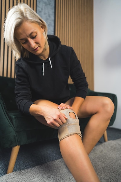 Mujer que usa un soporte protector de rodilla aparatos ortopédicos anatómicos para la fijación de la rodilla
