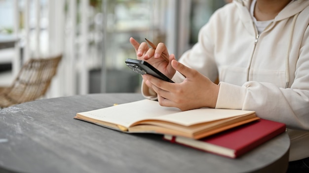 Una mujer que usa su teléfono para desplazarse por sus redes sociales mientras está sentada en un café