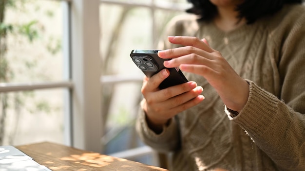 Foto una mujer que usa su teléfono inteligente para desplazarse por su teléfono mientras se relaja en un café