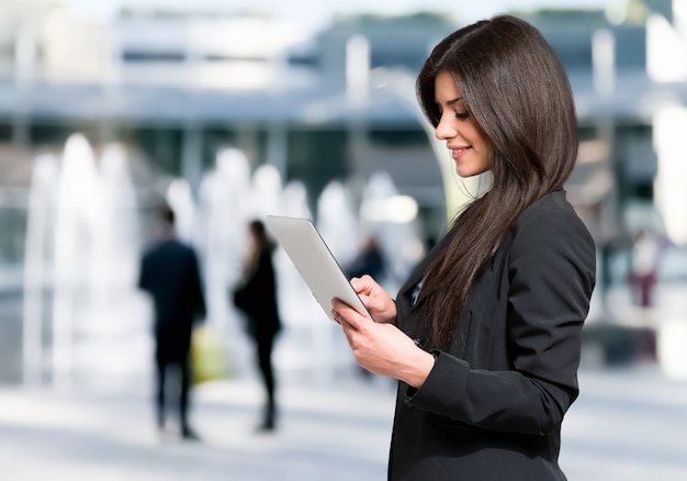 Mujer que usa una tableta al aire libre en un entorno urbano moderno