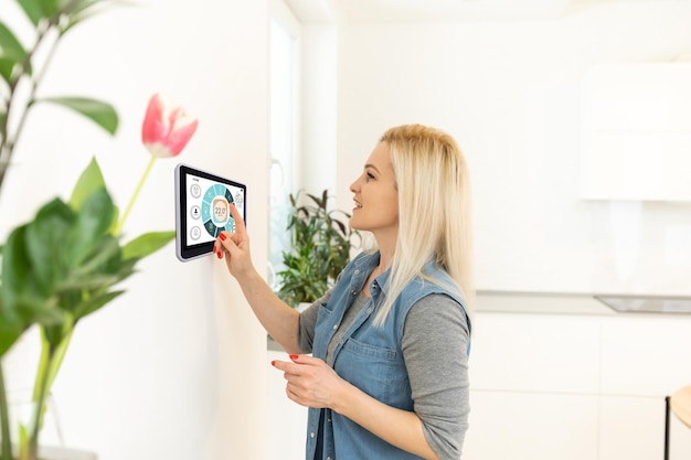 Mujer que usa la tableta en la pared Smart House.