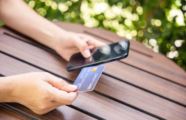 Mujer que usa tarjeta de crédito y teléfono inteligente durante la pantalla de diapositivas para encontrar el producto