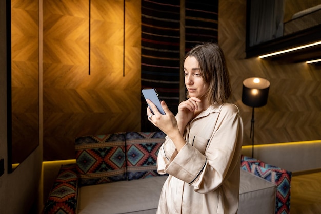 Mujer que usa el teléfono en el apartamento moderno