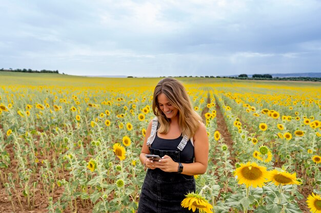 Una mujer que usa un teléfono celular entre girasoles.