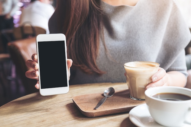 Foto mujer que usa el teléfono elegante con la taza de café