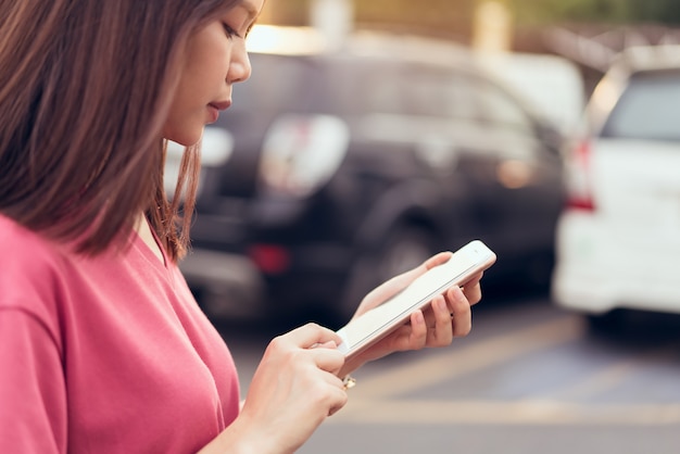 Foto mujer que usa el teléfono inteligente para la aplicación en el coche desenfoque de fondo.