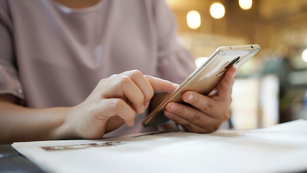 mujer que usa el teléfono inteligente en la cafetería.