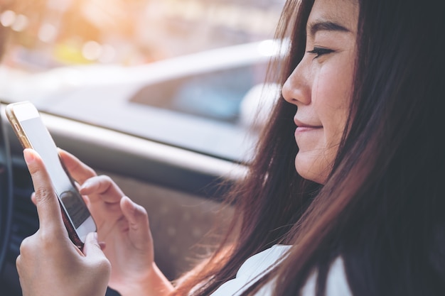 Mujer que usa el teléfono inteligente en el coche