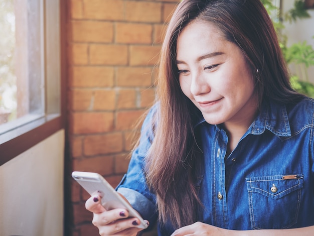 Mujer que usa el teléfono inteligente y la computadora portátil