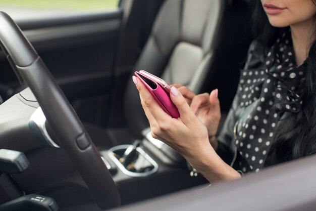 Mujer que usa teléfono inteligente. Interior borroso del coche