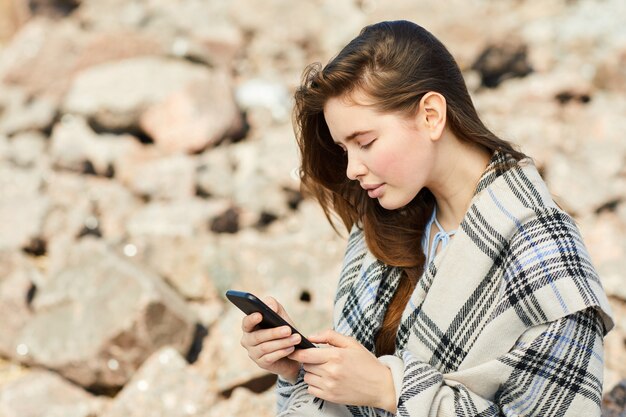 Mujer que usa el teléfono inteligente por mar