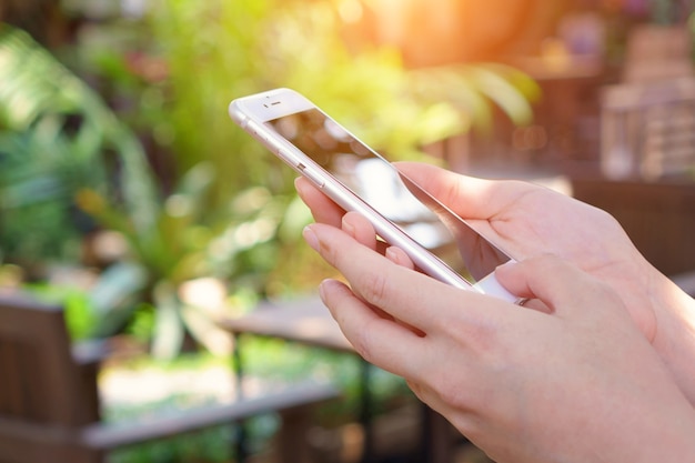 mujer que usa el teléfono inteligente móvil al aire libre en el fondo de la naturaleza