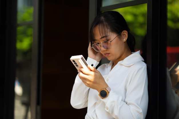 mujer que usa un teléfono inteligente mujer asiática ocupada trabajando en el teléfono móvil en un espacio de trabajo de oficina moderada atractiva hermosa mujer de negocios asiática que trabaja en la oficina en casa