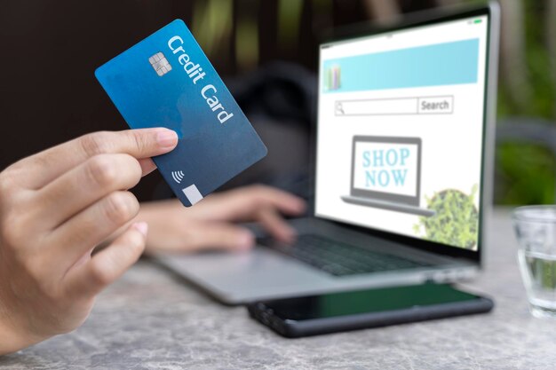 Mujer que usa un teléfono inteligente y una tarjeta de crédito para comprar en línea en una cafetería