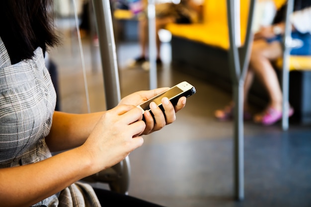 Mujer que usa el teléfono inteligente, teléfono móvil en el metro