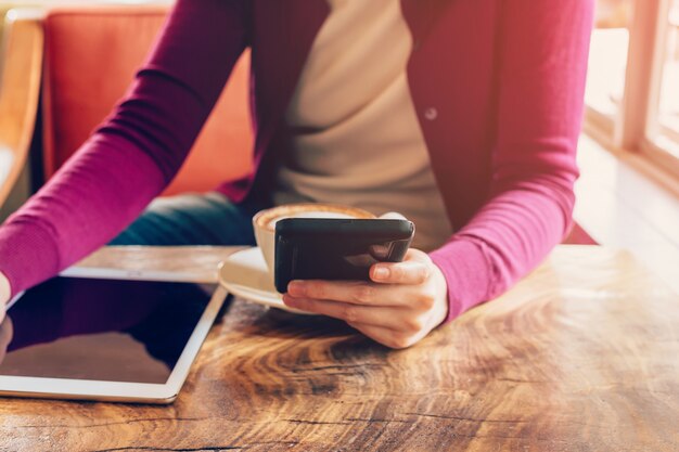 Mujer que usa el teléfono móvil en café. Mujer con tableta y café.