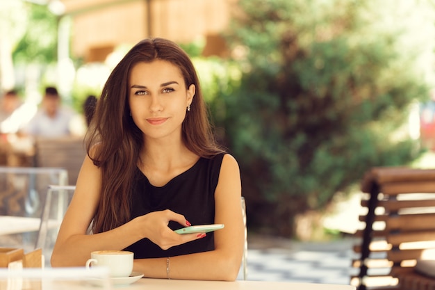 Mujer que usa el teléfono móvil en la cafetería