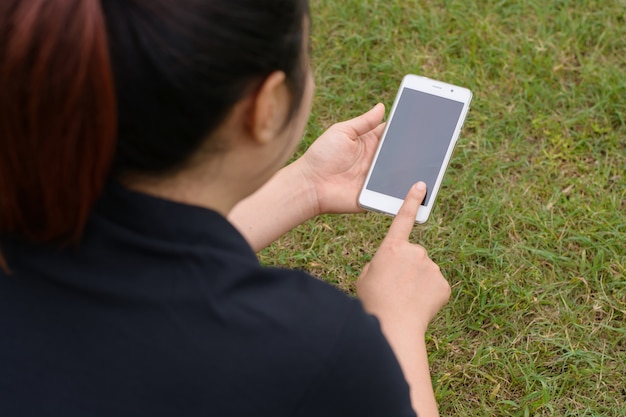 Mujer que usa el teléfono móvil inteligente en el parque.