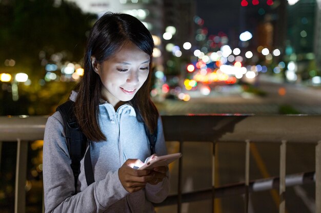 Mujer que usa el teléfono móvil en la noche