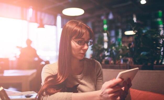 Mujer que usa un teléfono móvil en restaurante, cafetería, bar